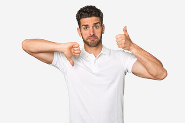 Fototapeta premium Young handsome man isolated showing thumbs up and thumbs down, difficult choose concept