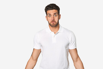 Young handsome man isolated shrugs shoulders and open eyes confused.