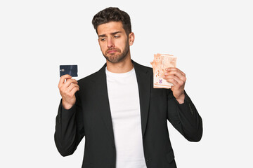 Young businessman comparing payment methods, holding euros in one hand and a credit card in the other.