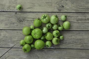 Green tomato on wooden background. Raw green tomato on table for dinner
