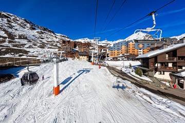 Ski slope in the ski resort of Val Thorens in the French Alps - Snowy track going through a village...