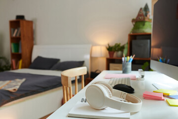 Desk in kids room with computer, headphones and opened notebook