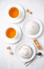 Cinnamon roll bun with cream glaze with cups of tea