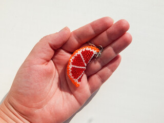 Orange fruit keychain lies on a woman's palm