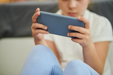 Cropped image of preteen girl using mobile appwhen playing game or watching short videos