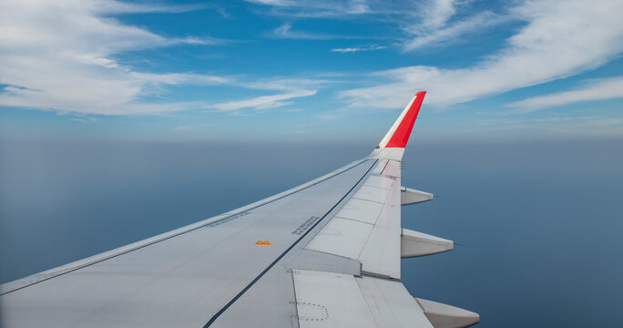 Aeroplane wing closeup view while in sky with clouds