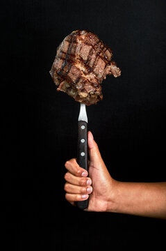 MANO SOSTIENDO CON TRINCHE CARNE BIFE