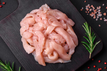 Raw chicken fillet cut into strips with spices and herbs