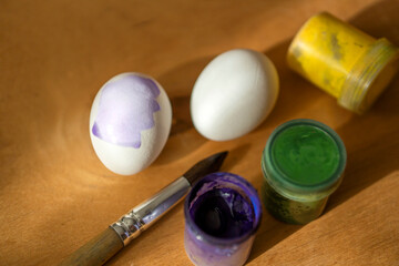chicken eggs and paints with a brush on a wooden surface. Easter. children's entertainment