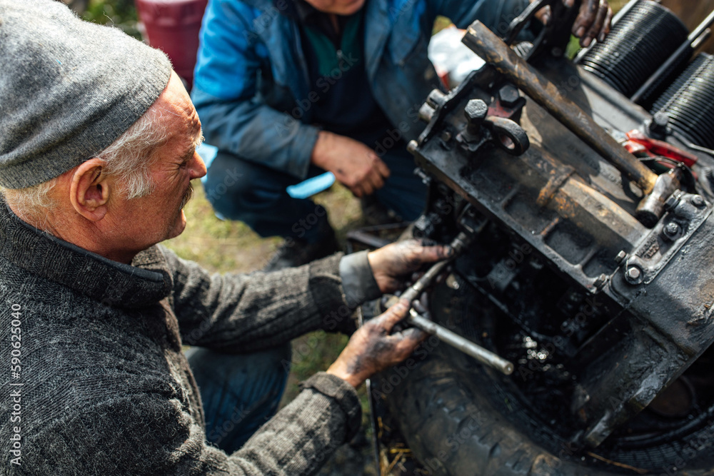 Wall mural tractor car engine repair at home, old man repairs the engine.