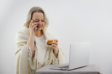 View over the shoulders of a sick couple in blankets using a laptop for an online conference with their doctor. woman with a fever are warmed by tea and have temperature