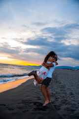 Sunset Romance: Man Carrying Woman on Beach