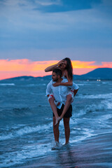 Fototapeta na wymiar Sunset Romance: Man Carrying Woman on Beach