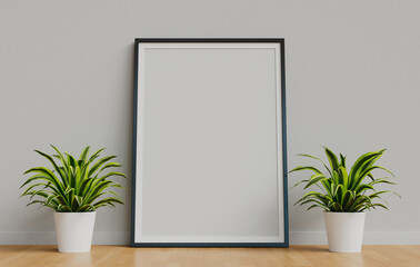 Framed poster mockup resting on the floor between two decorative plants