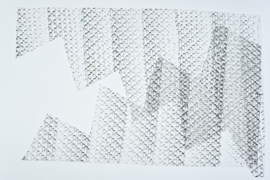 frottage technique featuring a grid or net pattern on tracing paper and photographed on a white backlit surface