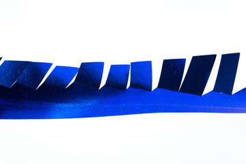 cut metallic blue paper object with fringe isolated on a blank surface