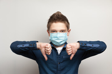 european boy with medical mask on face shows dislike