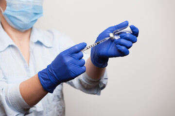 hands of a nurse in medical gloves dialing a vaccine or medicine for injection into the syringe