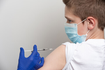 Medical and vaccination topic. Hands of nurse with syringe making vaccine injection to caucasian boy
