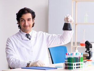 Young handsome chemist working in the lab