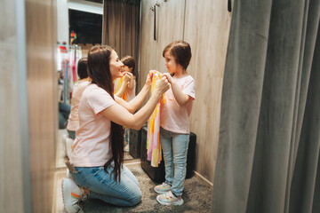 mother and daughter buy clothes. mother and little girl trying on clothes in the shop