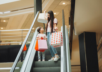 mother and little girl on the escalator in the mall.Mother and daughter in the mall. A young mother...