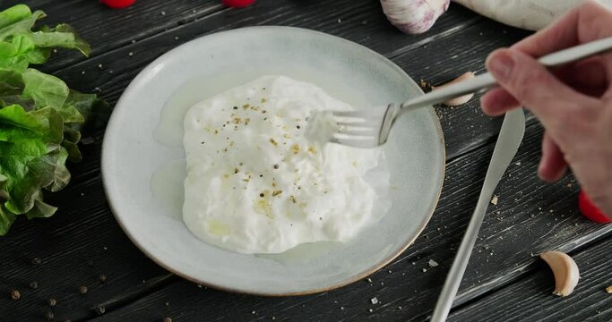 Stracciatella cheese. Italian Stretched curd cheese soaked in milk, Stracciatella di bufala, person tasting cheese with fork, curd fresh cheese made of shreds, video clip, high quality 4k footage