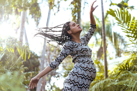 young pregnant woman with braids dancing as free spirit