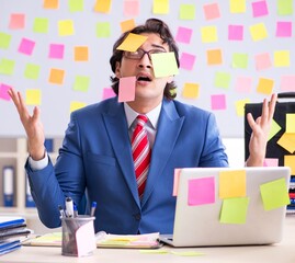 Young male handsome employee in conflicting priorities concept
