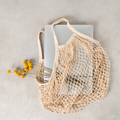 silver laptop with yellow flowers in beige string bag