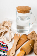 Fototapeta na wymiar a jug of water and wooden kitchen utensils with string bag and wooden tray