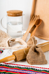 a jug of water and wooden kitchen utensils with string bag and wooden tray