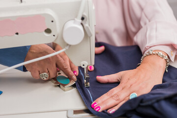 Atelier process needle detail. Unrecognizable woman hand on a sewing machine doing handmade fabric