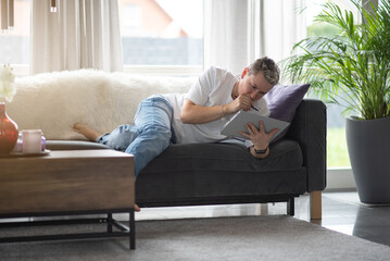 A woman is sitting on the couch and working on the laptop