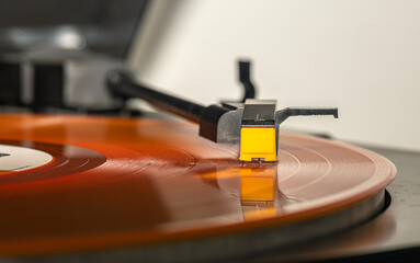 Fototapeta na wymiar It makes a melody sound as it hovers over the needle of an orange long play record player.