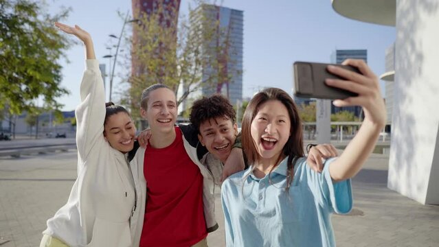 Happy boys and girls taking smiling selfie. Group of multiracial young people using smartphone at campus university. High quality photo