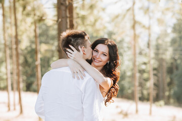 Young happy couple in love hugging smiling and having fun in the mountains. High quality photo. A girl in a beautiful white dress