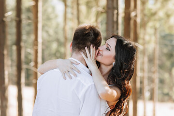 Fototapeta premium Young happy couple in love hugging smiling and having fun in the mountains. High quality photo. A girl in a beautiful white dress