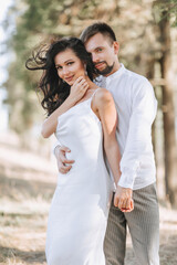 Fototapeta premium Young happy couple in love hugging smiling and having fun in the mountains. High quality photo. A girl in a beautiful white dress. Portrait photo