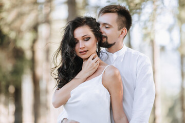 Fototapeta premium Young happy couple in love hugging smiling and having fun in the mountains. High quality photo. A girl in a beautiful white dress. Portrait photo