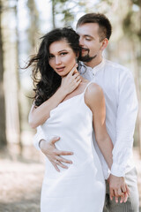 Obraz premium Young happy couple in love hugging smiling and having fun in the mountains. High quality photo. A girl in a beautiful white dress. Portrait photo