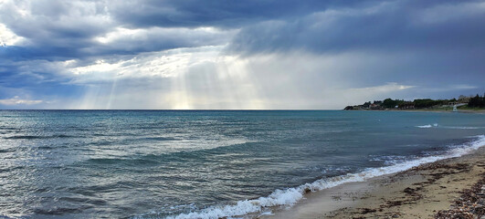 Stormy waves of the sea under a dark stormy sky and sunbeams. beauty in nature. the calm before the storm. the rays of the sun break through the dense layers of clouds
