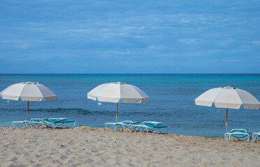 Three Tan Beach Umbrellas under Blue Sky.