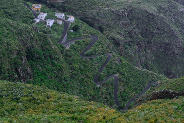 Pueblo en la cima de montaña con carretera en zigzag de descenso con vegetación verde