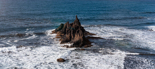 Roque volcánico entre olas en costa canaria