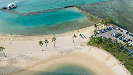 Beautiful ocean lagoon overview with white sand and palm trees in Honolulu Hawaii. Aerial drone top-down view.