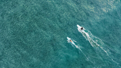 Surfers on a wave on a long surfboard in Waikiki Honolulu Hawaii. Aerial drone top-down view.