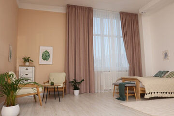 Stylish room interior with comfortable furniture and beautiful window curtains