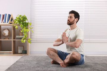 Man in earphones meditating at home, space for text