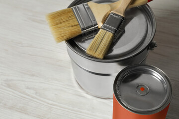 Can of orange paint, bucket and brushes on white wooden table, closeup. Space for text